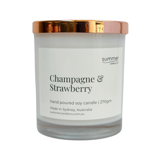 Hand-poured soy wax candle in a white jar with a rose gold lid, scented with Champagne & Strawberry. A sparkling, fruity blend with notes of ripe strawberries and bubbly champagne. Clean-burning and perfect for gifting or adding a festive touch.