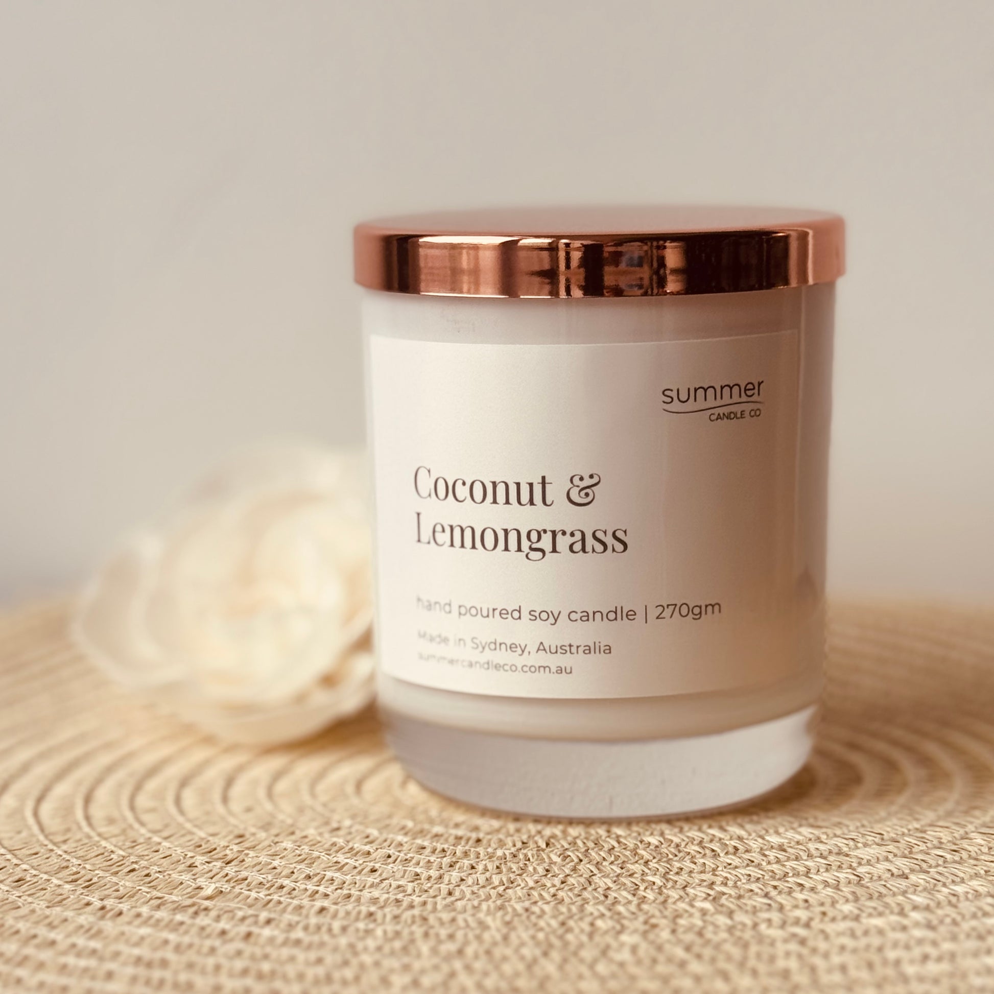 Hand-poured soy wax candle in a white jar with a rose gold lid, scented with Coconut & Lemongrass. A refreshing tropical blend with zesty lemongrass and creamy coconut. Clean-burning and perfect for gifting or creating a bright, energising space.