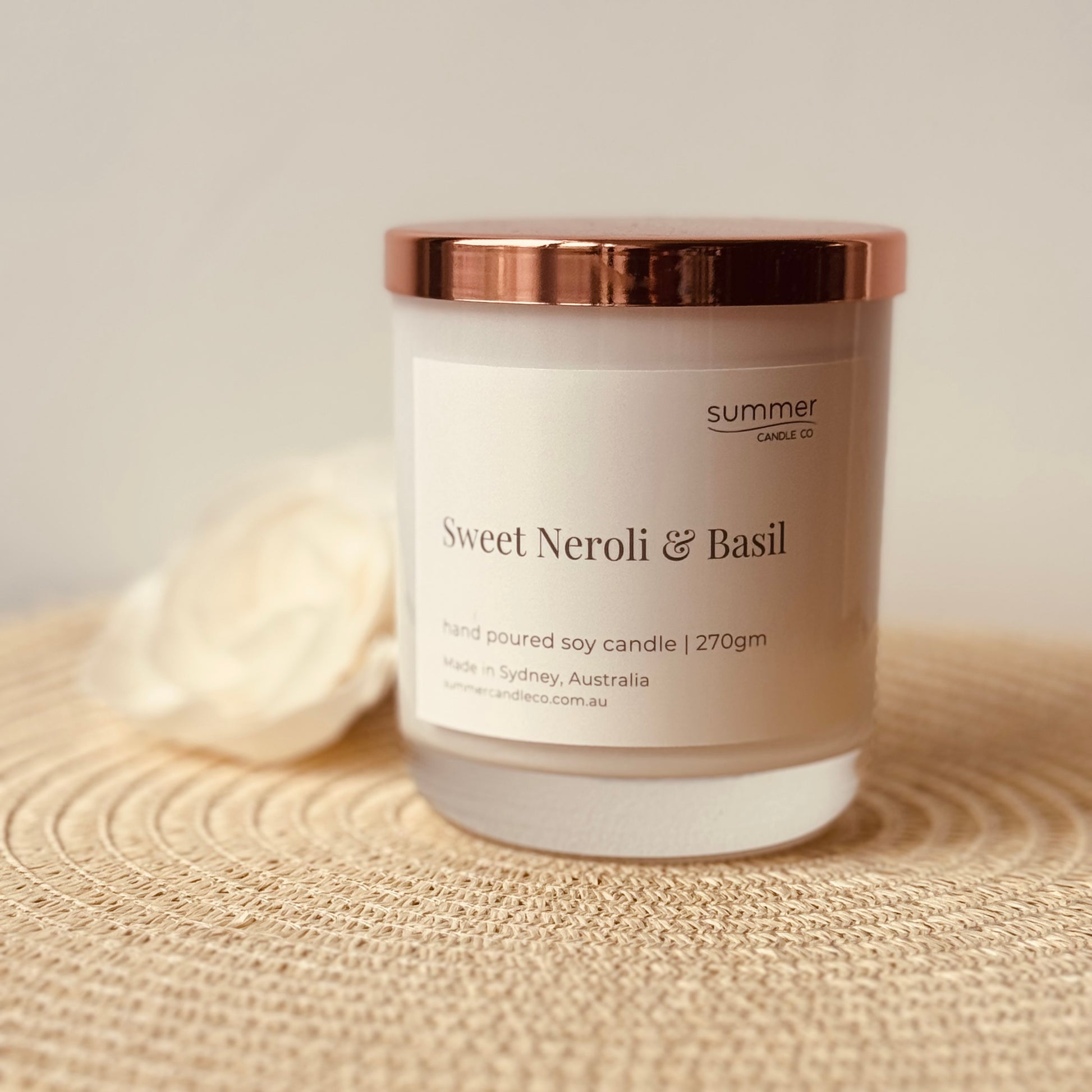 Hand-poured soy wax candle in a white jar with a rose gold lid, scented with Sweet Neroli & Basil. A fresh, uplifting blend of citrusy neroli and herbal basil. Clean-burning and perfect for gifting or creating a bright, refined atmosphere.