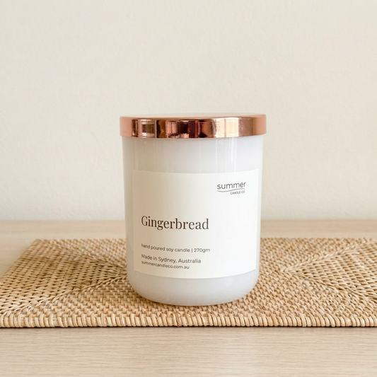 Gingerbread soy wax candle with rose-gold lid on a natural rattan placemat