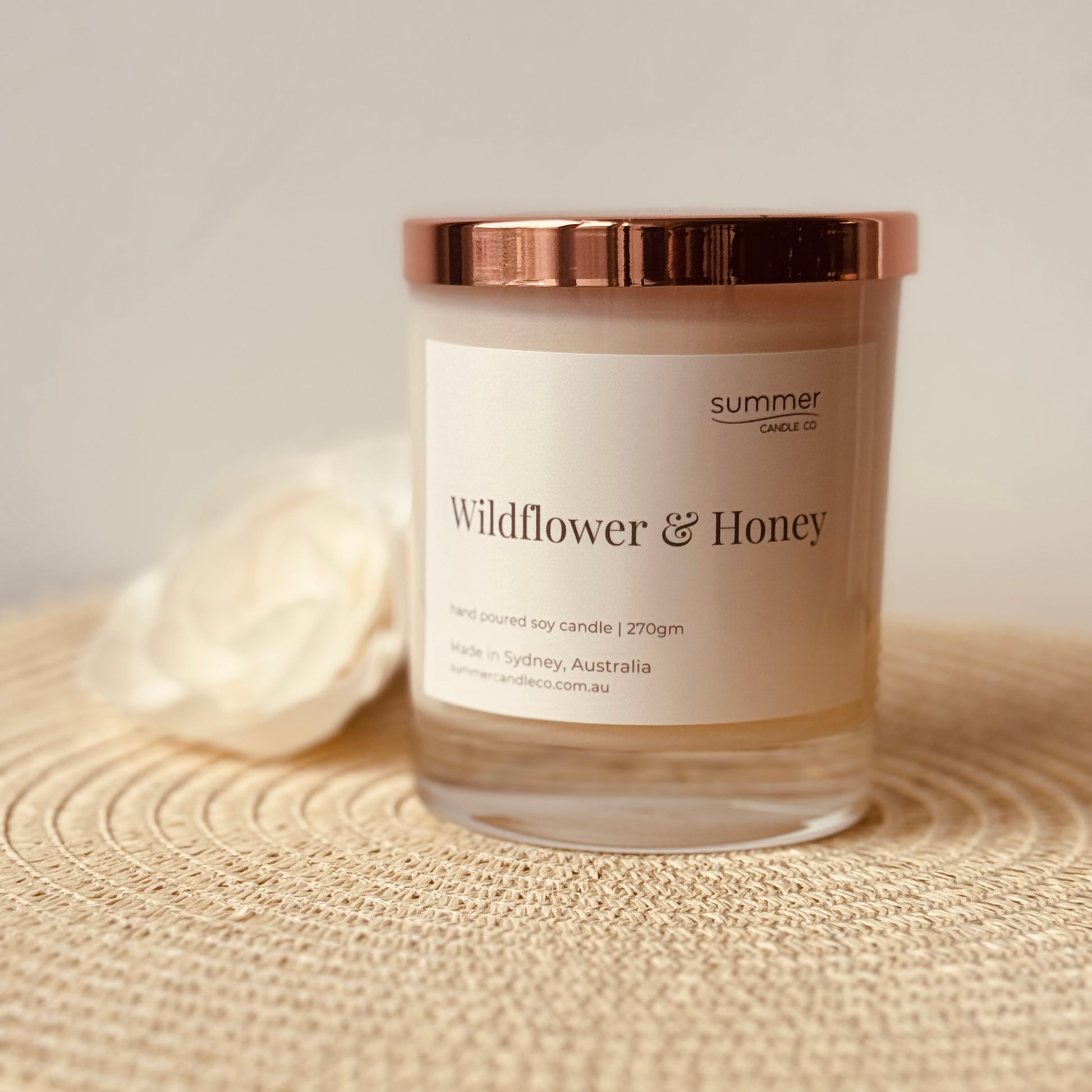 Hand-poured soy wax candle in a white jar with a rose gold lid, scented with Wildflower & Honey. A sweet, floral blend with notes of blooming wildflowers and golden honey. Clean-burning and perfect for gifting or creating a cozy, nature-inspired feel.