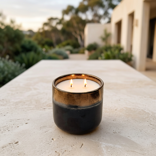 Black and gold citronella candle with two flames on a patio at dusk